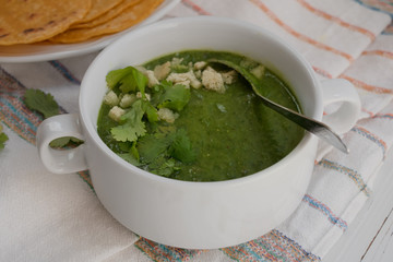 Spinach and putato cream soup served in white bowls on white table cloth