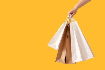 Female hand with paper shopping bags on color background