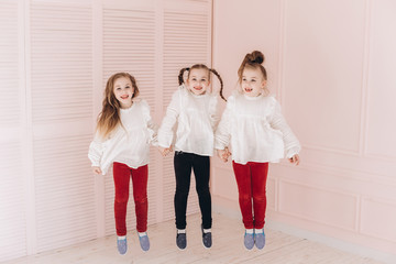 Happy cute adorable caucasian triplets girls posing at home together. Childhood, children, twins concept. Smiling girls playing together