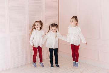 Fototapeta premium Happy cute adorable caucasian triplets girls posing at home together. Childhood, children, twins concept. Smiling girls playing together
