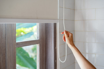 Woman pull rope, closed modern white jalousie