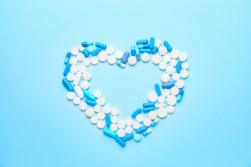 Heart made of pills on color background