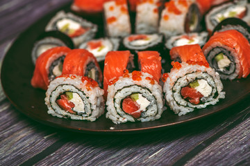 Various kinds of sushi served on dark plate macro