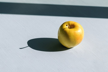 view from above yellow apple with a hard sunlight and deep shadow on a table, zero waste still life...