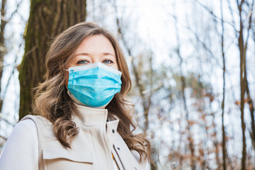 Frau mit Atemschutzmaske beim spaziergang im Park. Corona Virus Schutz.