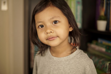 Young Asian girl with bookshelf in background