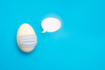 Osterei mit Mundschutz und Sprechblase auf blauem Hintergrund