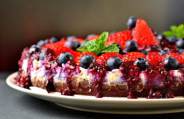 Cheesecake tart with fresh strawberries, blueberries and cherry jam. Low depth of field