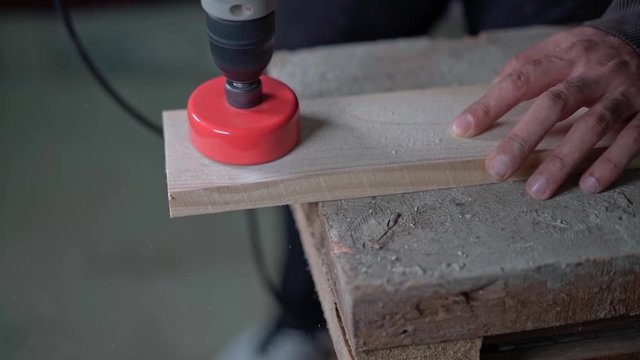 A drill with a circular nozzle cuts a circle in a wooden block
