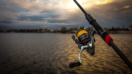 Fishing reel and rod, blurred background.