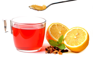 Cup of fruit tea, half pieced lemon, heap of dried tea and teaspoon of honey isolated on white background.