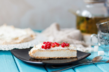 Piece of Pavlova on a plate on a blue table.