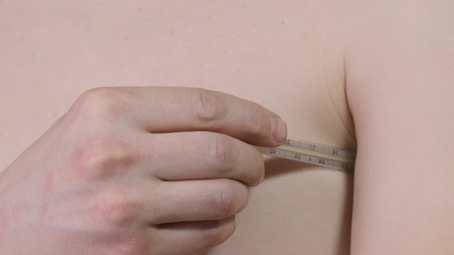 Man measures the temperature with a thermometer. Close up.