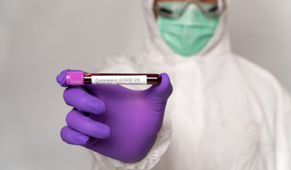 Doctors in the protective suits and masks are holding a positive blood test result for new rapidly outbreaking Coronavirus. Concept of spreading Coronavirus (COVID-19) around the world, USA, Europe