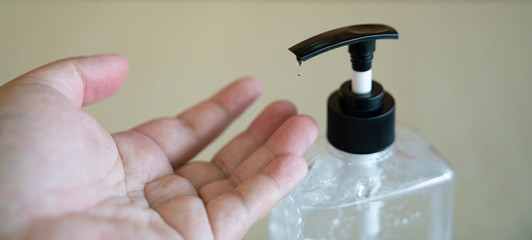 COVID-19 Close up man hands using wash hand sanitizer gel dispenser, against Novel coronavirus (2019-nCoV) at home. Home isolation, Auto Quarantine, Antiseptic, Hygiene and Healthcare concept.