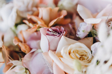 wedding ring lies on a bouquet of pink flowers and greenery