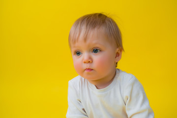 Healthy baby in white bodysuit sits on a yellow background, space for text