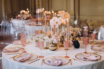 banquet tables with white tablecloths are in the hall of the old house, on the tables are flower...