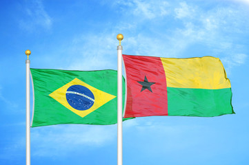 Brazil and Guinea-Bissau two flags on flagpoles and blue cloudy sky