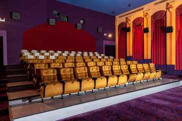 Large cinema theater interior with seat rows for audience to sit in movie theater premiere by cinematograph projector. The cinema theater is decorated in classical for luxury feel of movie watching. - obrazy, fototapety, plakaty