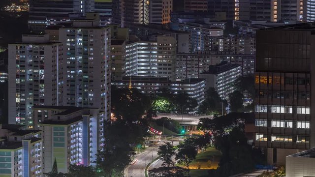 Aerial skyline with apartment buildings and skyscrapers of Singapore night timelapse. Traffic on streets. View from skybridge vewpoint