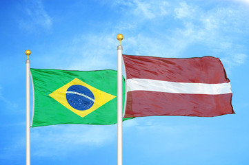 Brazil and Latvia two flags on flagpoles and blue cloudy sky