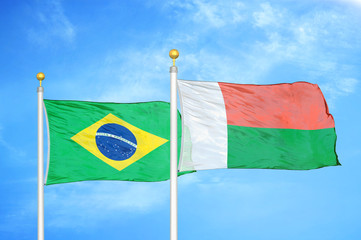 Brazil and Madagascar two flags on flagpoles and blue cloudy sky