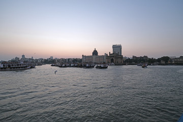 Fototapeta premium Taj Mahal hotel, Gateway of India and tourist boats in water of Arabian Sea on sunset in Mumbai, India