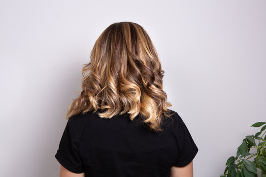 Shoulders portrait of a wavy-haired woman with bione and brown shades with balayage effect