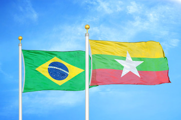 Brazil and Myanmar two flags on flagpoles and blue cloudy sky