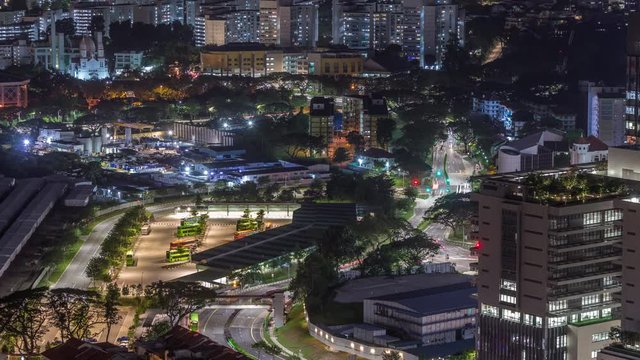 Aerial view to busy bus terminal in Singapore night timelapse. Kampong Bahru Bus Interchange with traffic on streets. Top view from skybridge viewpoint