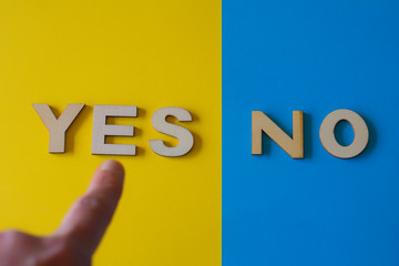 Yes or no. Finger pointing to the word yes. Blue and yellow background