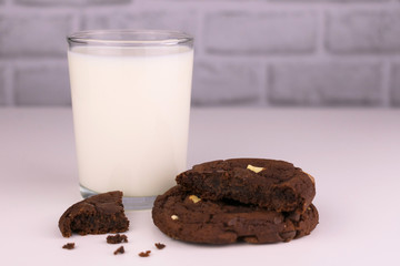  Milk in a glass and chocolate homemade cookies on a white background. Concept for a delicious snack.