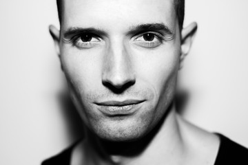 Black and white portrait photo of young happy man with unshaven face. Charming look high key black and white portrait
