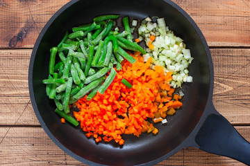 Step by step cooking risotto with vegetables, step 2 - laying out raw vegetables for frying in a pan, top view, selective focus