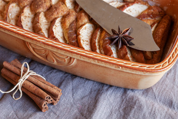 Close-up of apple pie, cinnamon sticks, anise and cutting knife in rustic style on a wooden background