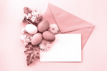 Festive arrangement: envelopes, painted eggs and flowers. Top view, flat lay, copy space. Toned in pink.