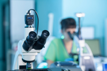 Female professional in uniform. Work with light microscope in research laboratory, test lab....