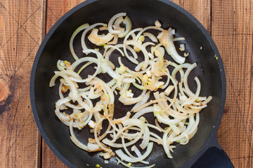 Step by step cooking of beef stroganoff, step 3 - frying chopped onions and garlic, top view, selective focus
