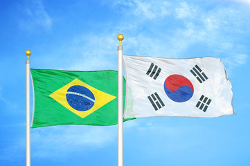 Brazil and South Korea two flags on flagpoles and blue cloudy sky