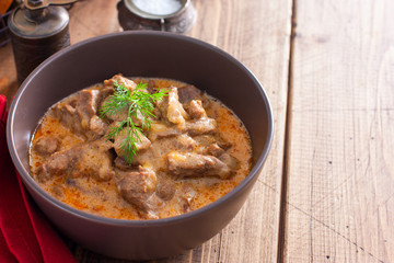 Traditional beef stroganoff in ceramic bowl on a wooden table, horizontal, copy space
