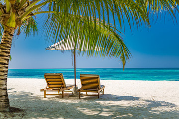 Travel background, beach scenery with palm leaves and umbrella close to sea. Amazing tranquility and relaxation concept. Tropical nature landscape