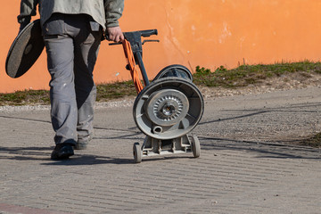 Naklejka premium Man pulls concrete grinding and polishing machine on wheels
