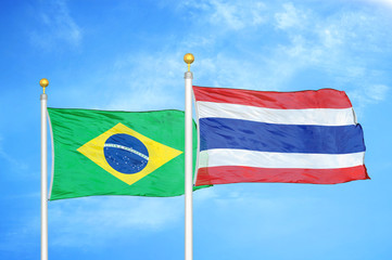 Brazil and Thailand two flags on flagpoles and blue cloudy sky