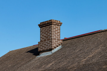 a new brown brick chimney on an unfinished roof