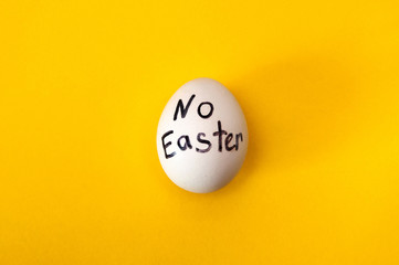 Cancellation of Easter celebration due to pandemic. The inscription No Easter with a marker on a white egg on a bright yellow background