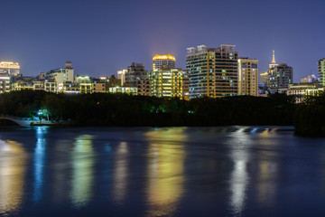 Fototapeta premium Nocny widok miasta Sanya z jasnymi wielokolorowymi iluminacjami budynków, konstrukcji, dróg, chodników, słupów, mostów.