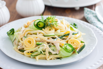 Salad with fresh cucumbers, chicken and fried egg pancakes on a white plate, selective focus