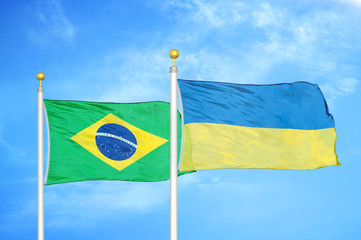 Brazil and Ukraine two flags on flagpoles and blue cloudy sky