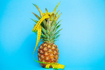 Ripe pineapple with tape measure on a blue background